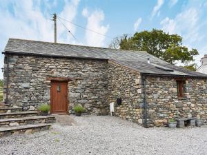 a stone cottage with a wooden door and a stone wall at Hilltoft Barn in Dockray