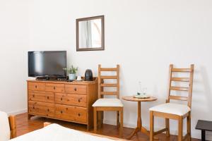 a living room with a tv on a dresser and two chairs at HOTEL LEMONIADA in Lućmierz