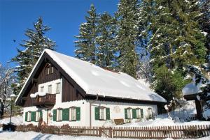 ein schneebedecktes Haus mit einem Zaun und Bäumen in der Unterkunft Villa BeLucky in Oberammergau