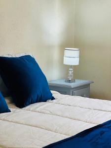 a bed with a blue pillow and a lamp on a table at Nogueira Country House in Fundão