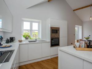 uma cozinha branca com armários brancos e um balcão em Brens Barn em Bedale