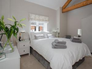 Un dormitorio con una cama blanca con toallas. en Brens Barn en Bedale