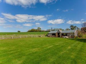 una casa de campo con una valla y un gran campo de césped en Brens Barn en Bedale