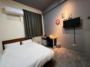 a bedroom with a bed and a desk and a television at 森林寓 in Minxiong