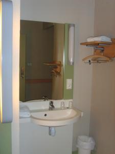 a bathroom with a sink and a mirror at ibis budget L'Isle Adam in LʼIsle-Adam