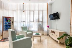 ein Wohnzimmer mit 2 Stühlen und einem TV in der Unterkunft Hotel Andrea´s in Los Cristianos