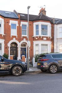 two cars parked in front of a brick house at Two Bedroom Apartment in Tooting in London
