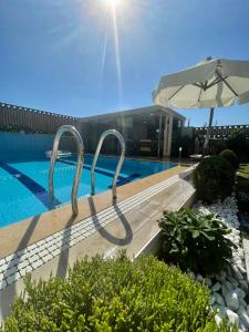 a swimming pool with an umbrella next to a building at Villa Annabèll in Belek