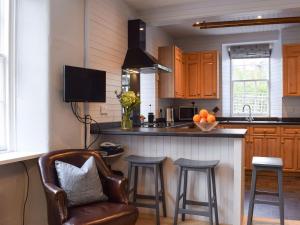 a kitchen with a counter with stools and a sink at Ardchoille Cottage in Fortingall