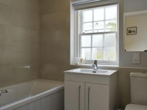 ein Bad mit einem Waschbecken, einer Badewanne und einem Fenster in der Unterkunft Ardchoille Cottage in Fortingall