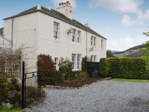 ein weißes Haus mit einem Zaun davor in der Unterkunft Ardchoille Cottage in Fortingall