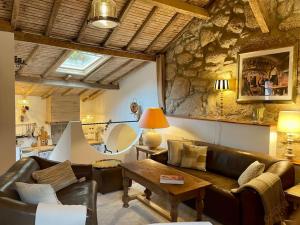 a living room with leather furniture and a stone wall at Cottage da Minha Terra 1890 in Geres