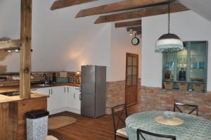 een keuken met een tafel en een roestvrijstalen koelkast bij Forreset - leśny apartament, sauna i balia jacuzzi in Gietrzwałd