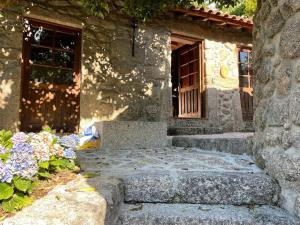 a stone building with a door and some flowers at Cottage da Minha Terra 1890 près d'un lac in Geres