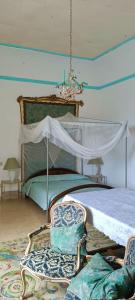 a bedroom with a bed with a canopy and two chairs at Palazzo Caracciolo in Gerace
