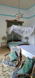 a bedroom with a bed with a canopy and chairs at Palazzo Caracciolo in Gerace