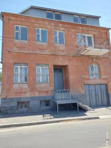un edificio de ladrillo con un banco delante de él en Mazmanyan 181, en Gyumri