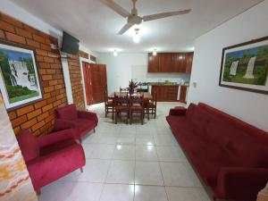 a living room with red couches and a dining room at Charaí Lodge in Puerto Iguazú