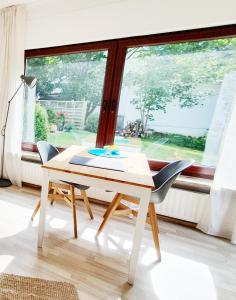 una mesa y sillas blancas en una habitación con ventana en Ferienwohnung Gartenblick - Idylle am Travetal en Bad Oldesloe