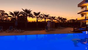 a swimming pool with palm trees and a sunset at Exclusives Apartment Mountainview Residence in Belek
