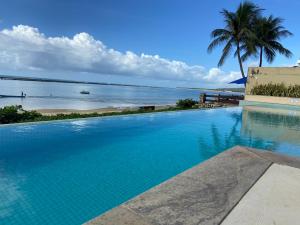 a swimming pool with a view of the ocean at Apartamento Barra Bali in Barra de São Miguel