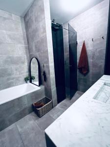 a bathroom with a shower and a tub and a sink at 2x Bedroom Luxury Apartment with amazing views! in Reykjavík