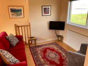 a living room with a red couch and a flat screen tv at Plockton, Camus Fearn Barn in Plockton