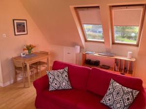 a living room with a red couch and a table at Plockton, Camus Fearn Barn in Plockton