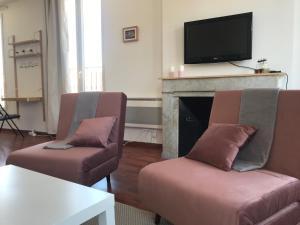 a living room with two chairs and a tv on a fireplace at Studio Moustier in Marseille