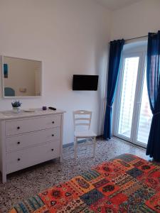 a bedroom with a dresser and a mirror and a chair at Casa del Mare in Ischia