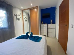 a bedroom with a white bed with blue sheets and a mirror at Oasis Cotillo in Cotillo