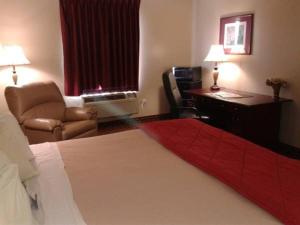 a hotel room with a bed and a desk and a chair at Rest Inn Fort Smith in Fort Smith