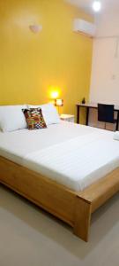 a large bed in a room with a yellow wall at Airport Lodge Lungi in Lungi