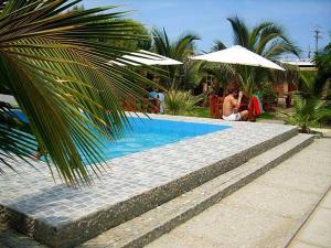 a woman sitting under an umbrella next to a swimming pool at Ariena in Los Órganos