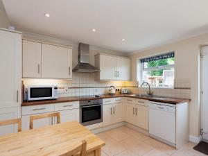 a kitchen with white cabinets and a wooden table at Oakridge in Salcombe