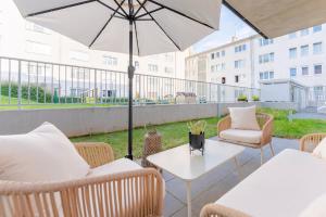 een patio met stoelen en een tafel met een parasol bij Garden.Lounge Krems am Steinertor in Krems an der Donau