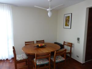 a dining room with a wooden table and chairs at Apartamento Pitangueiras in Guarujá