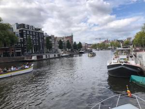 Due barche in un fiume con delle persone sopra. di Amsterdam Boat & Breakfast ad Amsterdam