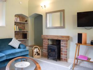 a living room with a blue couch and a fireplace at Coachman's Cottage in Pencombe