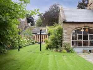 a garden with green grass and a building at Coachman's Cottage in Pencombe