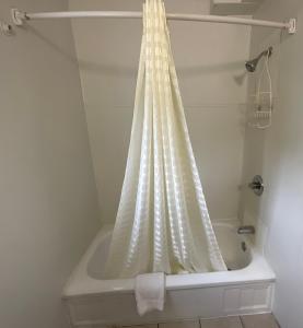 a bath tub with a shower curtain in a bathroom at Kansan Motel in Liberal