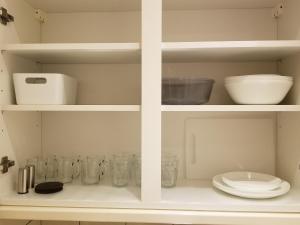 a white cabinet with glass dishes and bowls on it at London Luxury 2 bed studio 4 mins from Ilford Stn - FREE parking, WiFi, garden access in Ilford