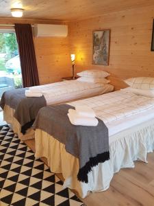 two beds in a room with wooden walls at Raselund Gård in Vinninga