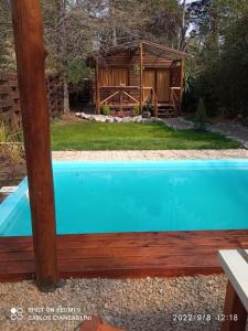 a blue swimming pool in front of a house at La Casa Del Arbol con pileta privada in Capilla del Señor