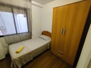 a small bedroom with a bed and a wooden cabinet at Sunny flat with huge terrace! Close downtown! in Alicante