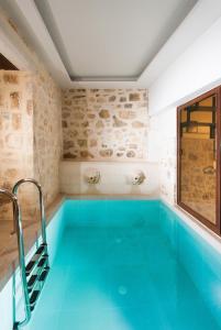 a swimming pool in a room with a blue swimming pool at Ali Vafi's Villa - Heated Jacuzzi & Indoor Pool in Maroulás