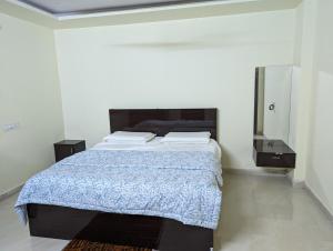 a bedroom with a bed with a blue blanket and a mirror at Ramya Grand in Visakhapatnam