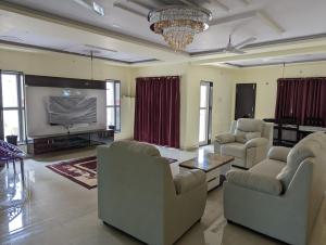 sala de estar con sofás y TV de pantalla plana. en Ramya Grand, en Visakhapatnam