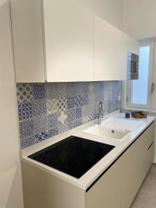 a kitchen with a sink and white cabinets at Elementi Luxury House in Otranto