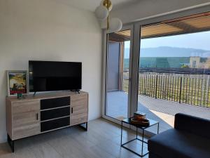 a living room with a flat screen tv and a balcony at New Great Apartment Bolzano with 25m pool in Bolzano